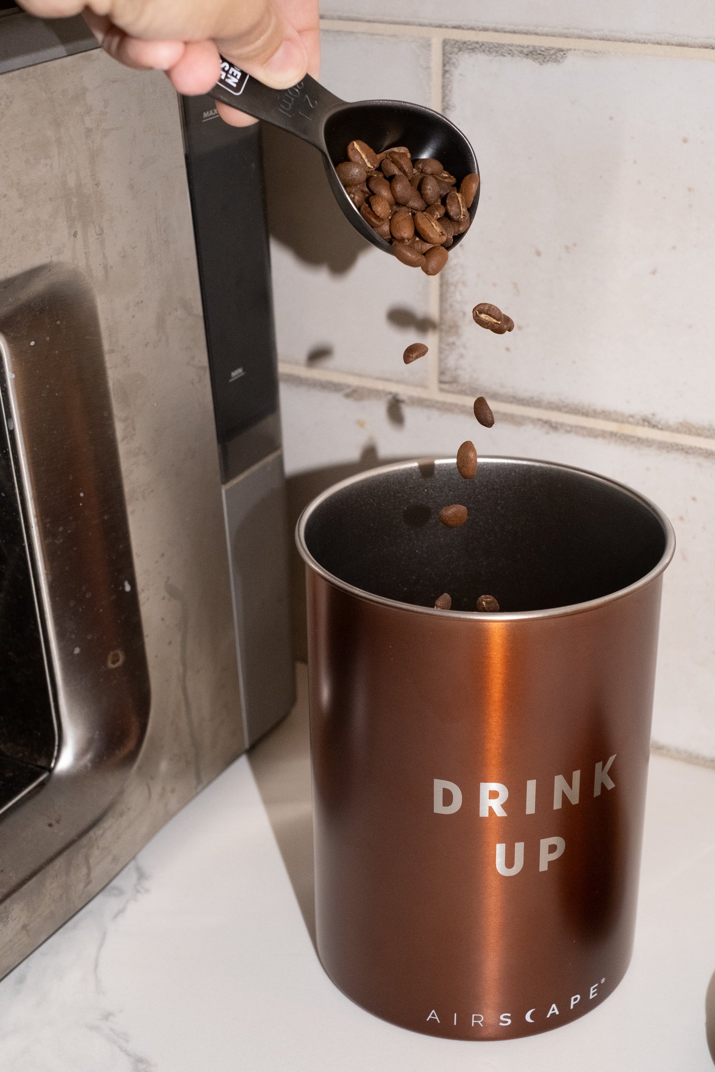 Image of coffee being poured into bronze coffee canister.