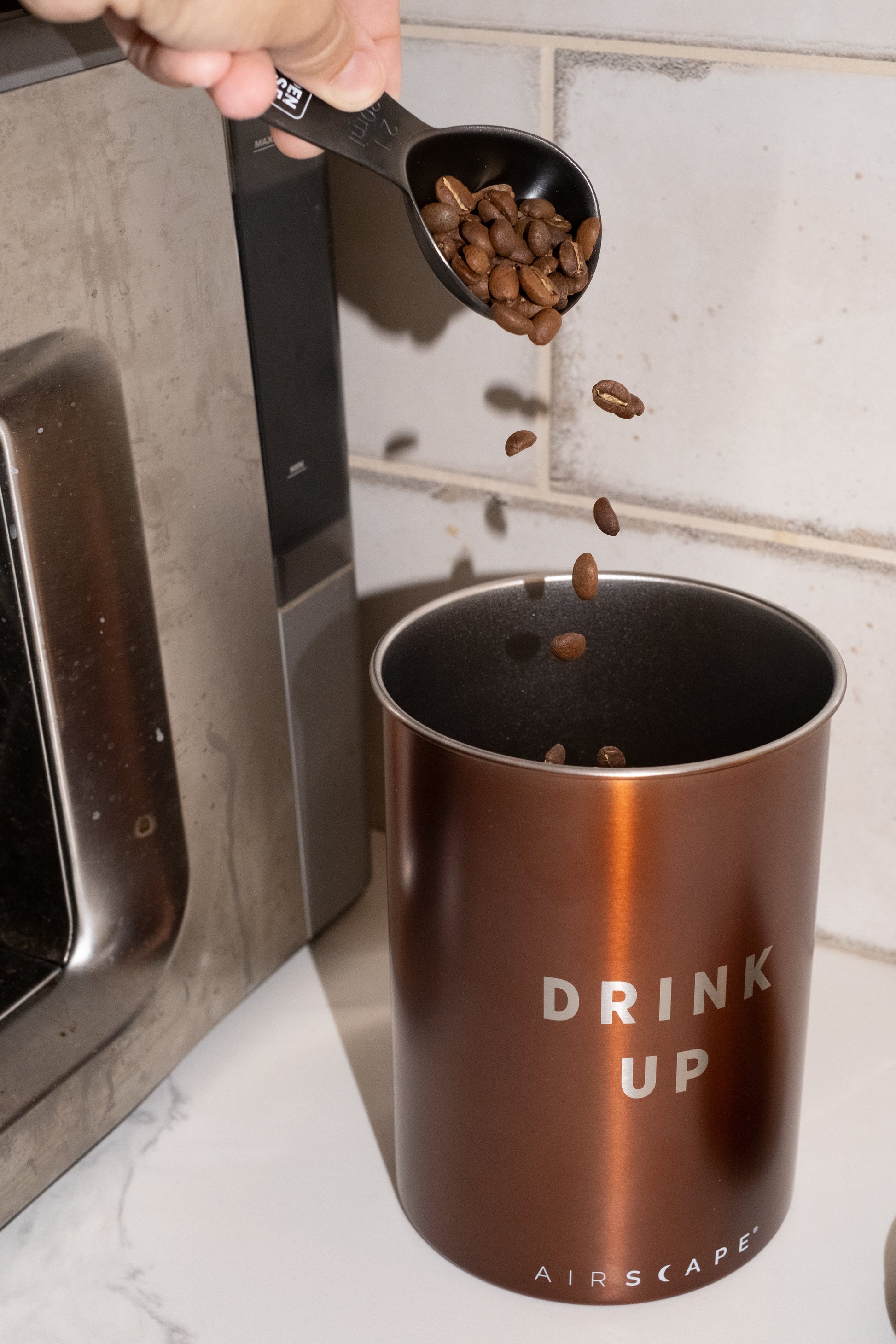 Image of coffee being poured into bronze coffee canister.