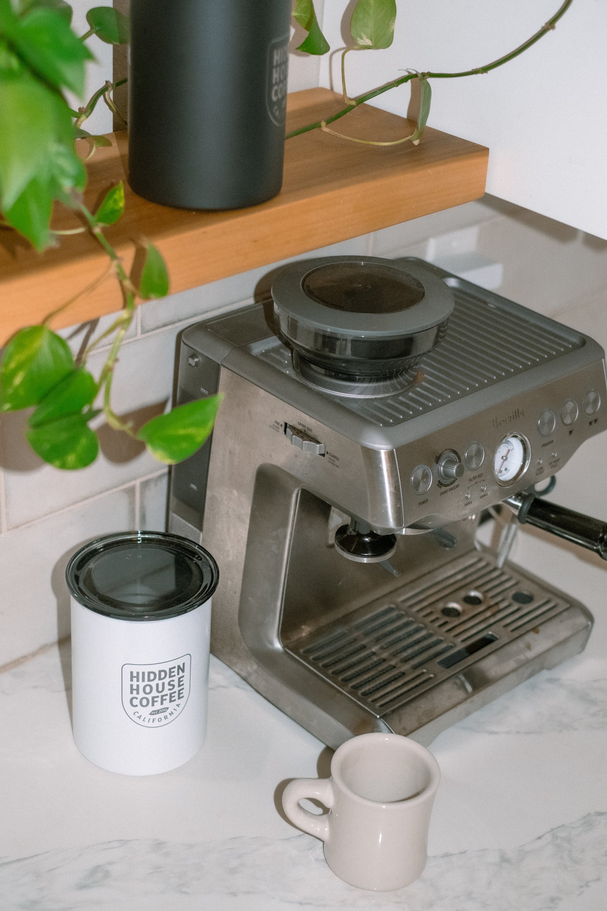 Coffee canister next to espresso machine.