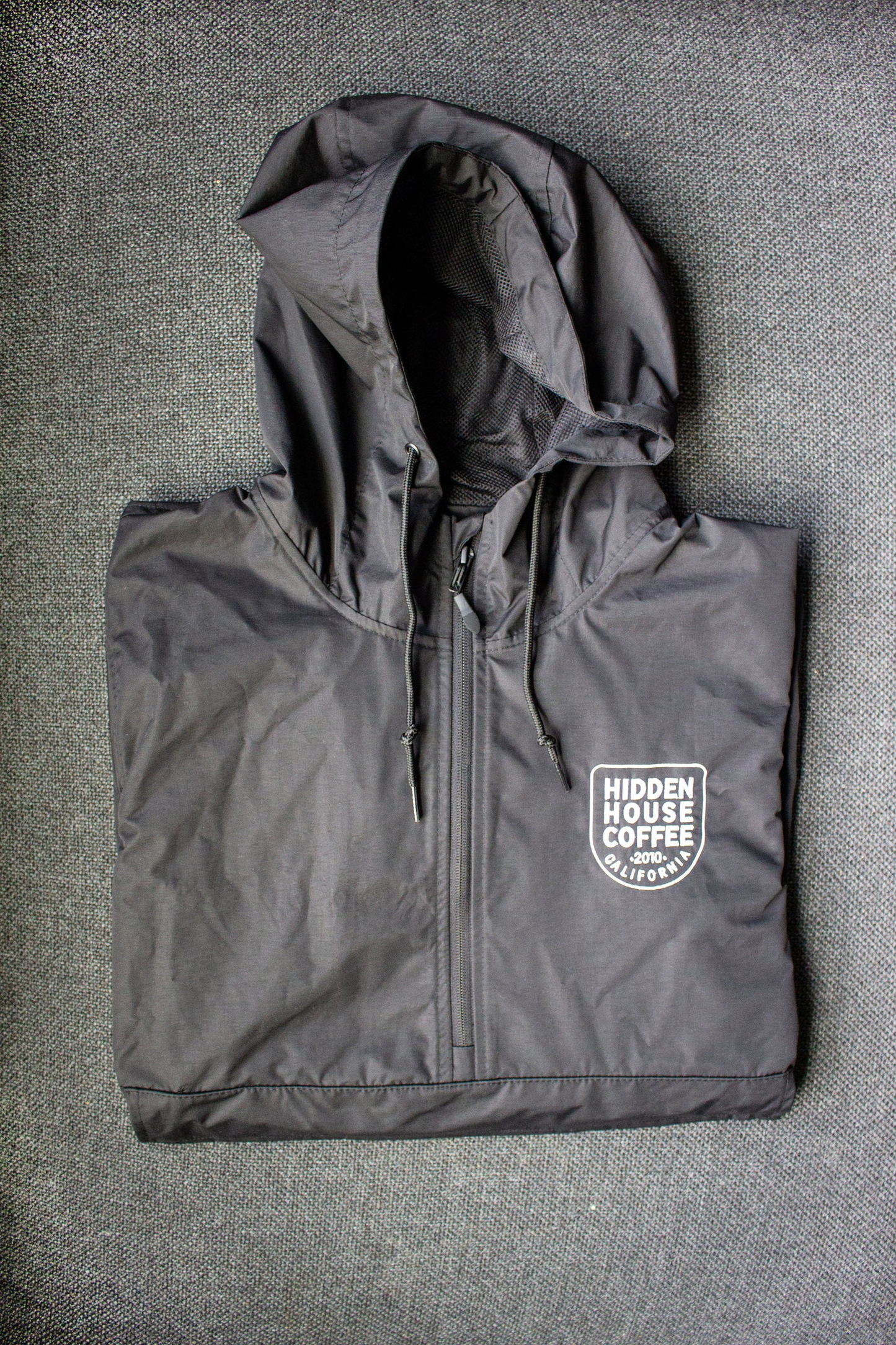Image of front of rain jacket, embroidered with hidden house coffee logo.