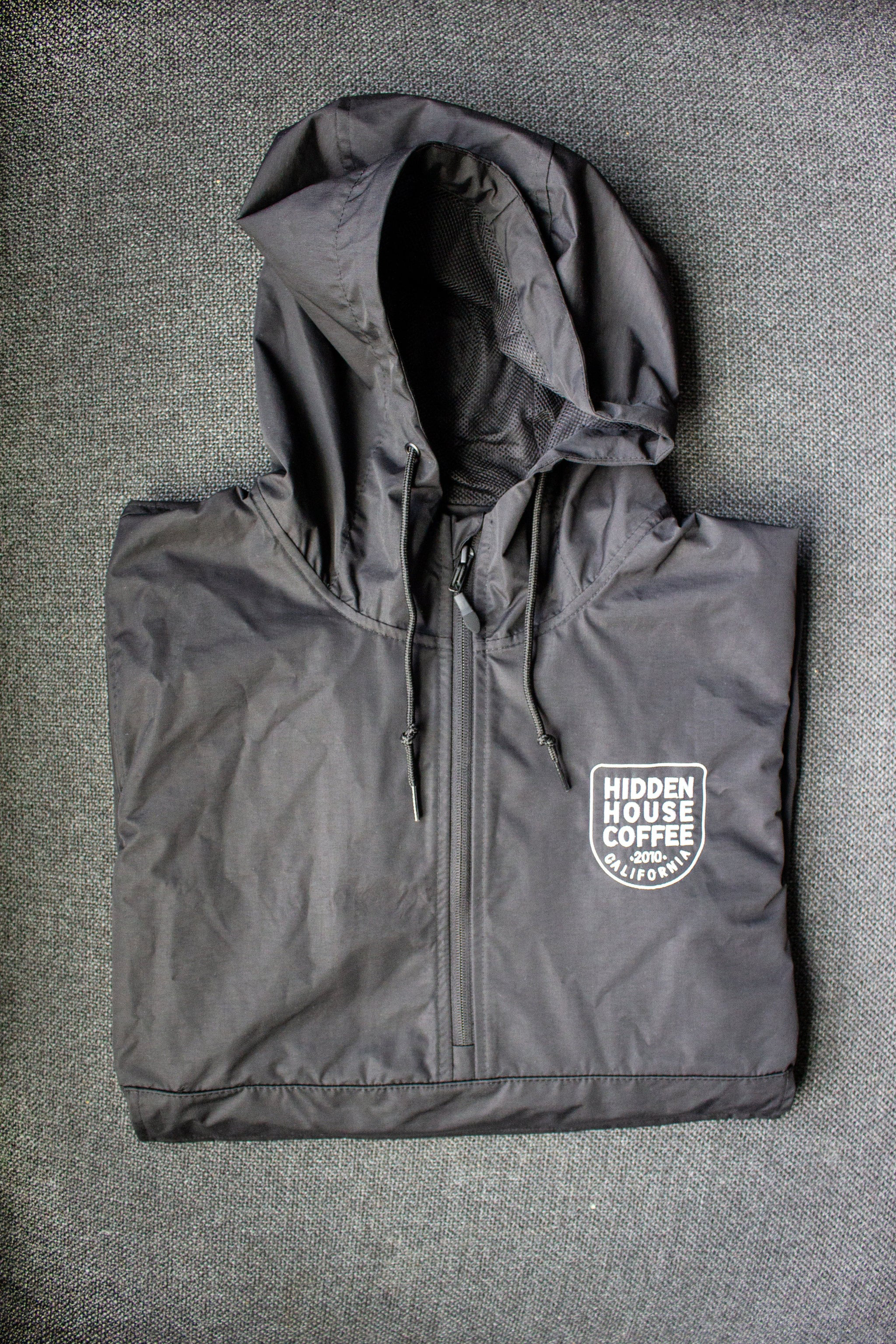 Image of front of rain jacket, embroidered with hidden house coffee logo.