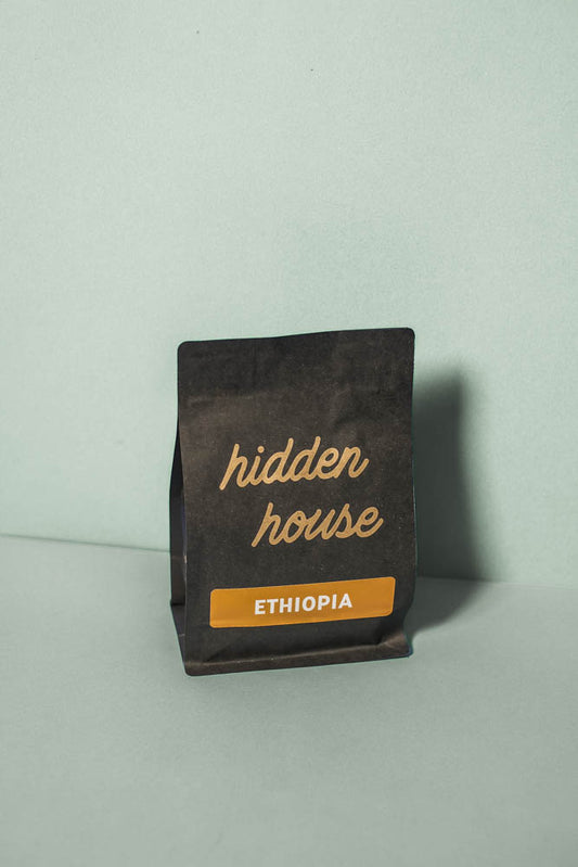 A picture of a black coffee bag with an orange sticker that says Ethiopia