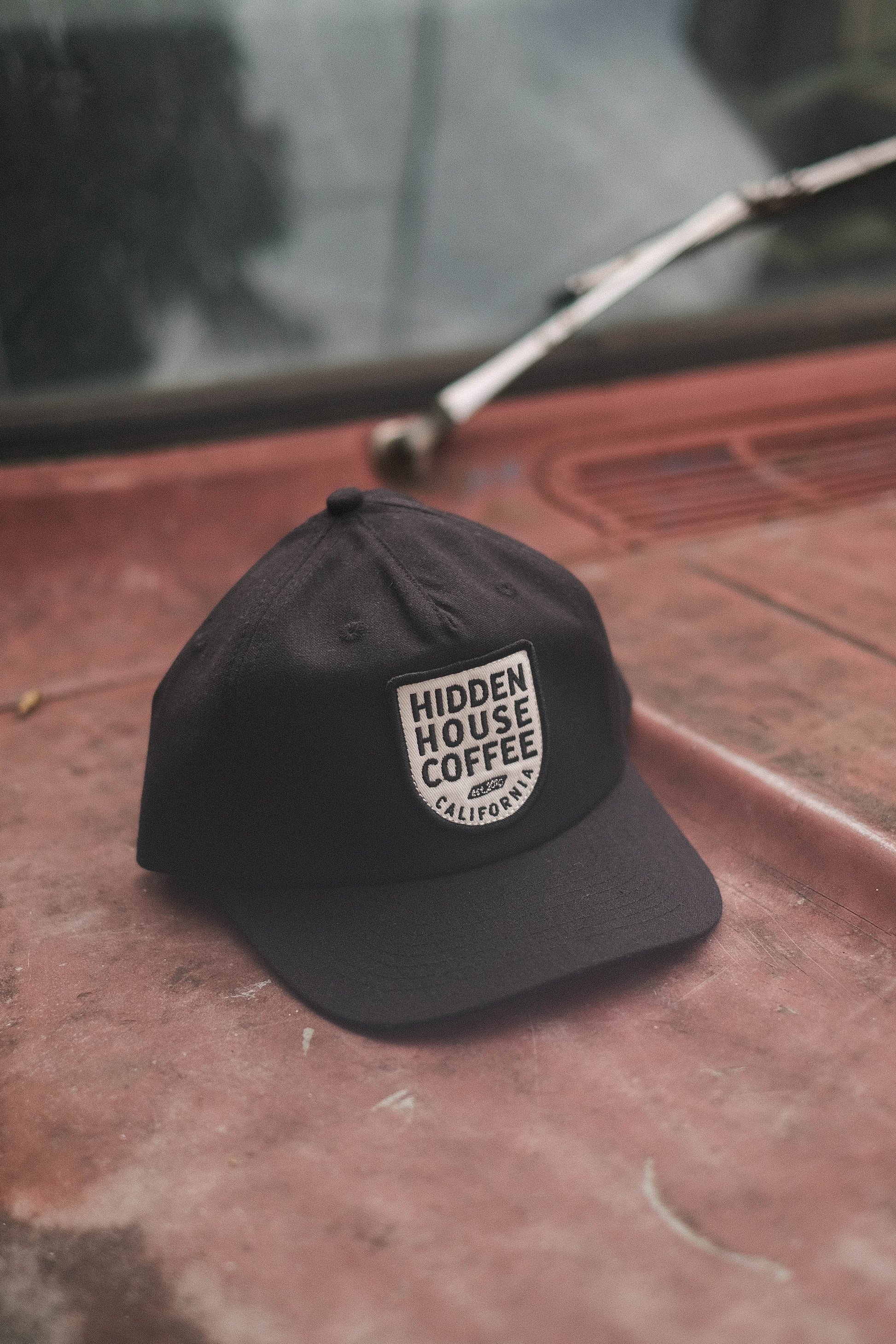 Image of black hat that has hidden house coffee embroidered on it.