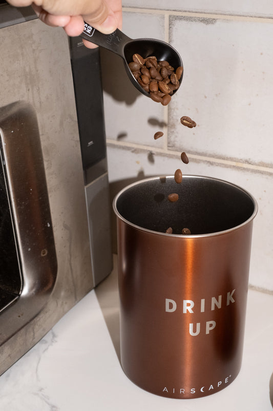 Image of coffee being poured into bronze coffee canister.