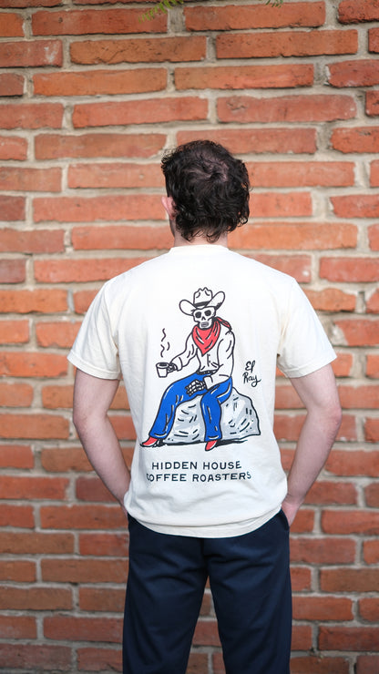 The back of the el ray t-shirt is shown. The art is drawn of a skeleton cowboy drinking coffee out of a mug. The bottom of the shirt design says "hidden house coffee roasters"