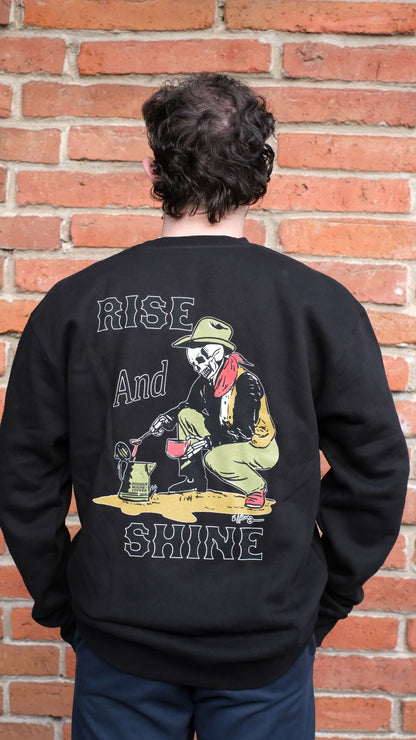 Photo of model wearing sweatshirt with "rise and shine" printed on the back, and el ray artwork.