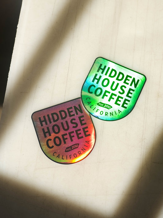 Image of holographic Hidden House logo sticker, showing reflection in the material.